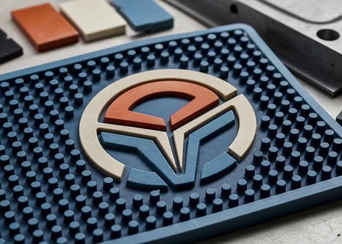 A vibrant, multi-colored custom PVC bar mat with a 3D embossed logo
