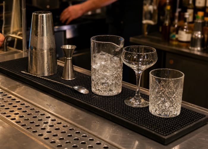 A long rectangular bar mat with multiple glasses and shakers, showcasing its functional size