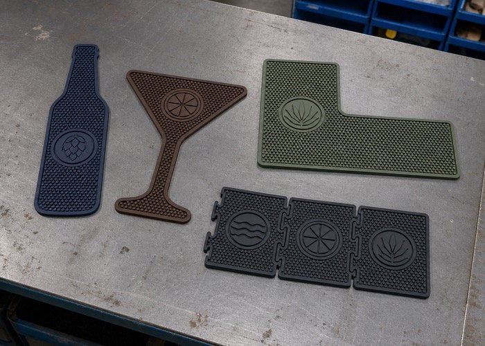 A collection of die-cut bar mats in the shape of a beer bottle, a cocktail glass, and a modular corner piece.